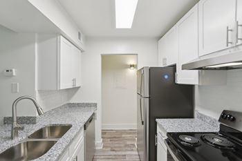 A modern kitchen with a black refrigerator and stove top oven.
